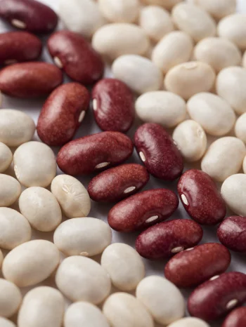Berbagai jenis kacang kering di meja kayu, dalam mangkuk dan tersebar