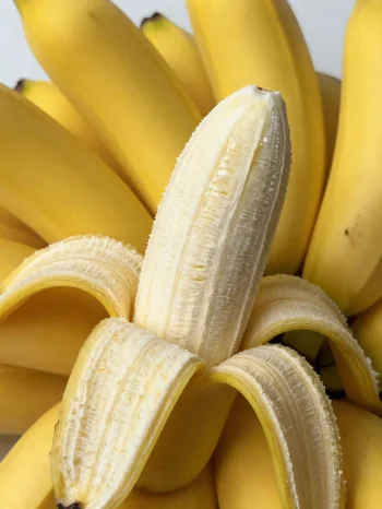 Pisang segar utuh dan iris dalam mangkuk dan di atas meja rustik