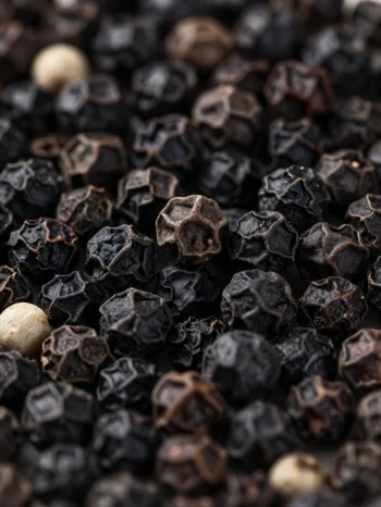 Butiran lada hitam dan lada bubuk dalam mangkuk keramik dan permukaan kayu