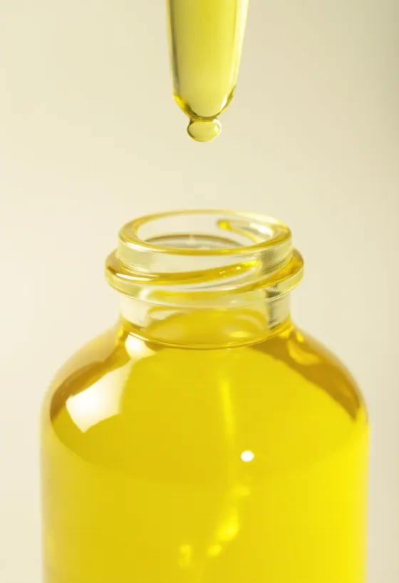 Minyak lemon dalam botol kaca kecil, irisan lemon segar dan kulit lemon