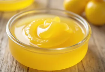 Ghee (minyak samin) dalam toples kaca dan sendok di atas meja kayu