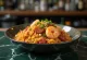 Hidangan nasi dengan udang merah muda, sosis, dan sayuran