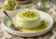 Kue panna cotta pistachio dihias dengan krim pistachio dan pistachio segar