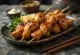 Momo yakitori paha ayam di tusuk sate, disajikan dengan wijen dan bawang daun segar